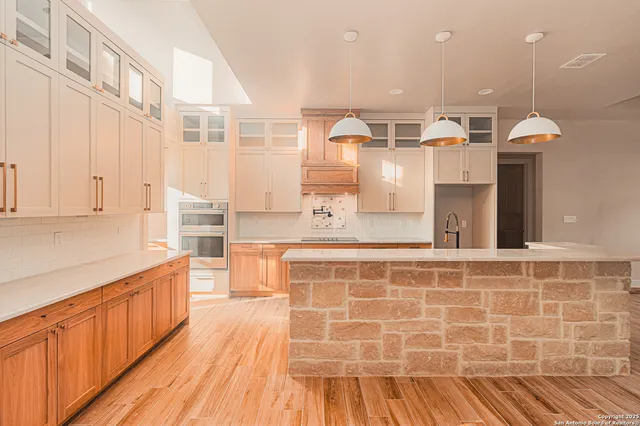 a large kitchen with stainless steel appliances a large counter top a stove and a refrigerator