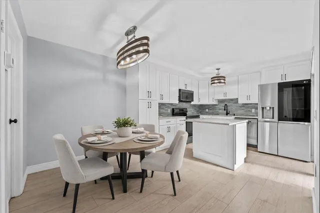 a kitchen with a dining table chairs and refrigerator