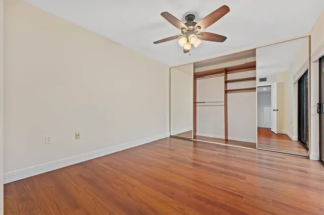 an empty room with wooden floor and ceiling fan