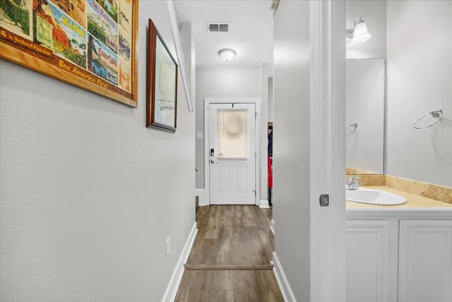 a view of a hallway with wooden floor and a bathroom