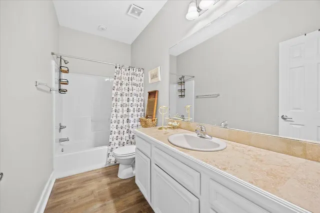 a bathroom with a granite countertop sink a toilet a shower and a mirror