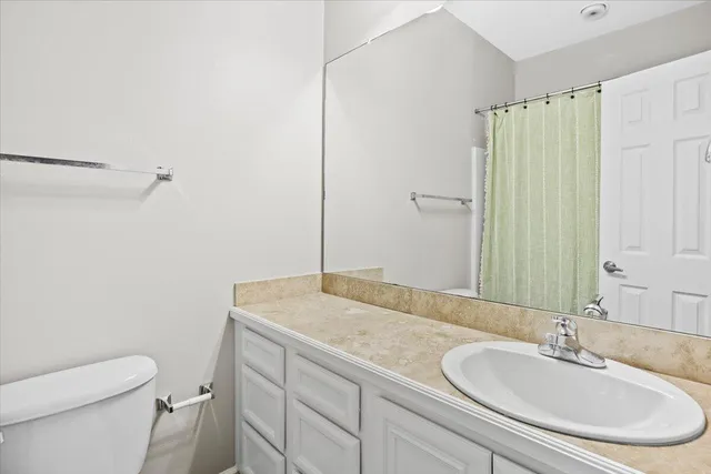 a bathroom with a granite countertop sink a toilet and a mirror