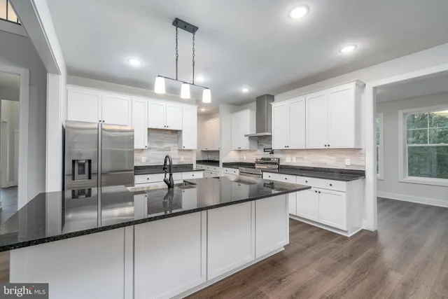 a kitchen with kitchen island granite countertop stainless steel appliances a sink a stove a refrigerator cabinets and a window