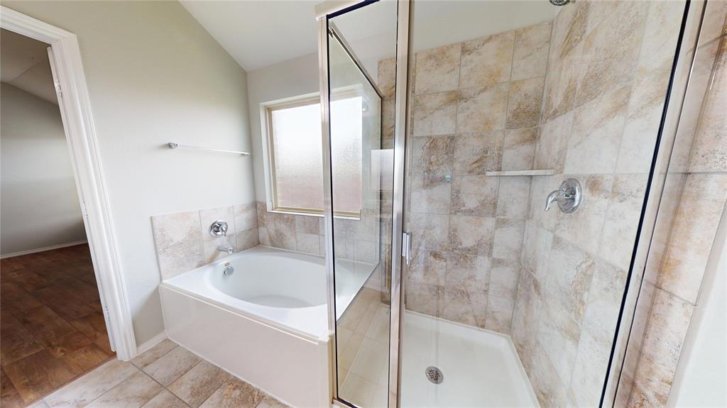 3101 Buckthorn Street Forney, TX 75126 - Photo 16 of 40 Bathroom featuring a white soaking tub with polished chrome fixtures, a tiled surround, and an adjacent shower enclosure with glass panels and a tiled interior