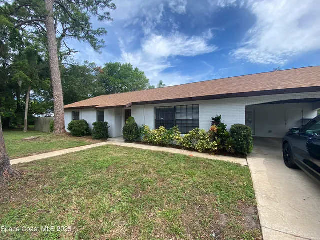 a view of a house with backyard and trees