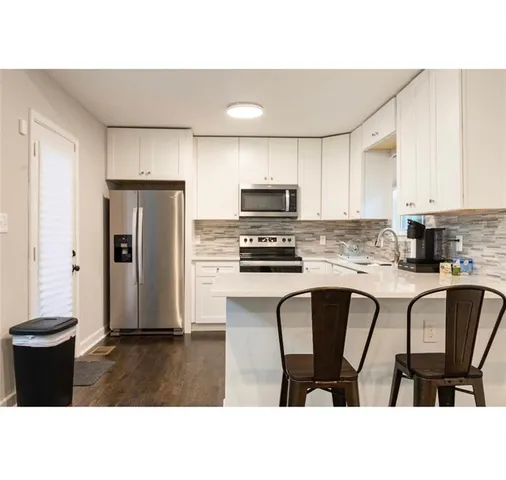 a kitchen with stainless steel appliances a refrigerator a stove a sink a dining table and chairs