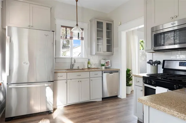 a kitchen with granite countertop a refrigerator a sink and wooden floors