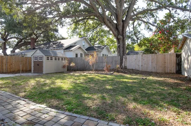 a view of a yard with a large tree and wooden fence