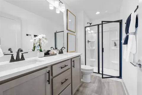 a bathroom with a double vanity sink toilet and shower