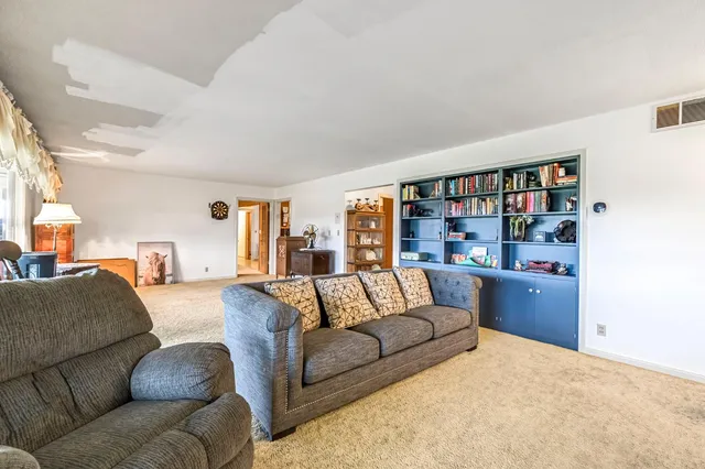 a living room with furniture flowers and a floor to ceiling window