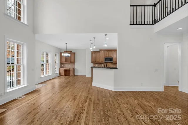 a view of kitchen and empty room with wooden floor