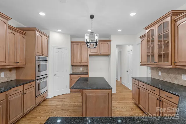 a kitchen with stainless steel appliances kitchen island granite countertop a refrigerator and a sink