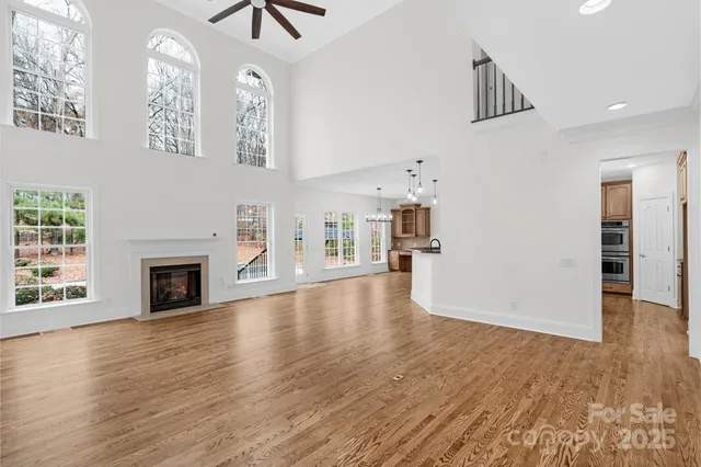 an empty room with wooden floor fireplace and windows