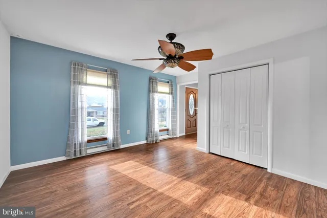 a view of an empty room with window and wooden floor