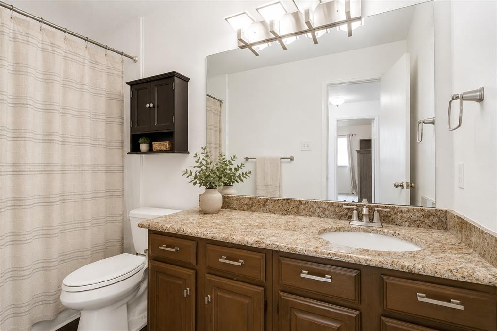 3438 Spring Willow Drive Grapevine, TX 76051 - Photo 13 of 23 Virtual Staged. Bathroom featuring a single vanity with a stone-finish countertop, wood-finish cabinetry, an undermount sink, and a wall-mounted mirror