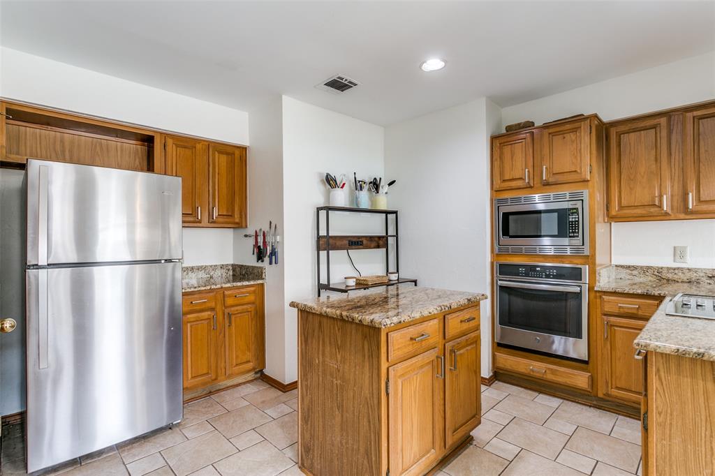 3438 Spring Willow Drive Grapevine, TX 76051 - Photo 7 of 23 Kitchen with stainless steel appliances, a center island, light stone counters, wood finish cabinetry, and recessed lighting
