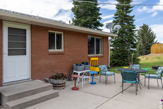 322 Bailey Creek Road Soda Springs, ID 83276 - Photo 27 of 32 Concrete patio area featuring a brick exterior, white framed windows, and a white screen door