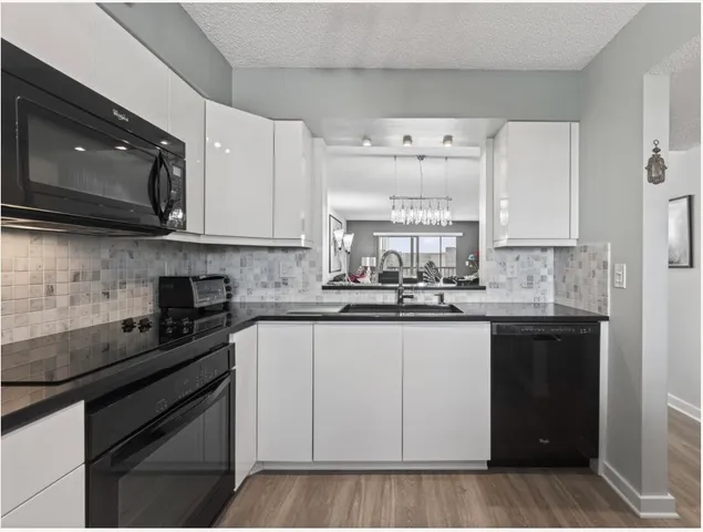 a kitchen with granite countertop white cabinets and black stainless steel appliances