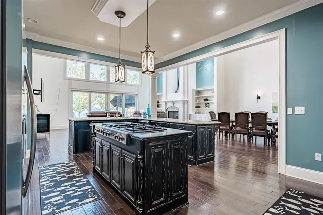 a kitchen with stainless steel appliances granite countertop a stove top oven a refrigerator a dining table and chairs with wooden floor