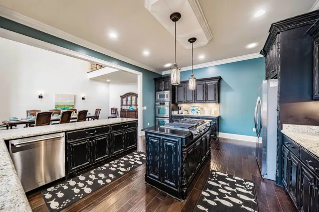 a kitchen with stainless steel appliances a stove a sink dishwasher a refrigerator white cabinets and wooden floor