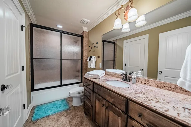 a bathroom with a granite countertop sink a toilet a mirror and shower