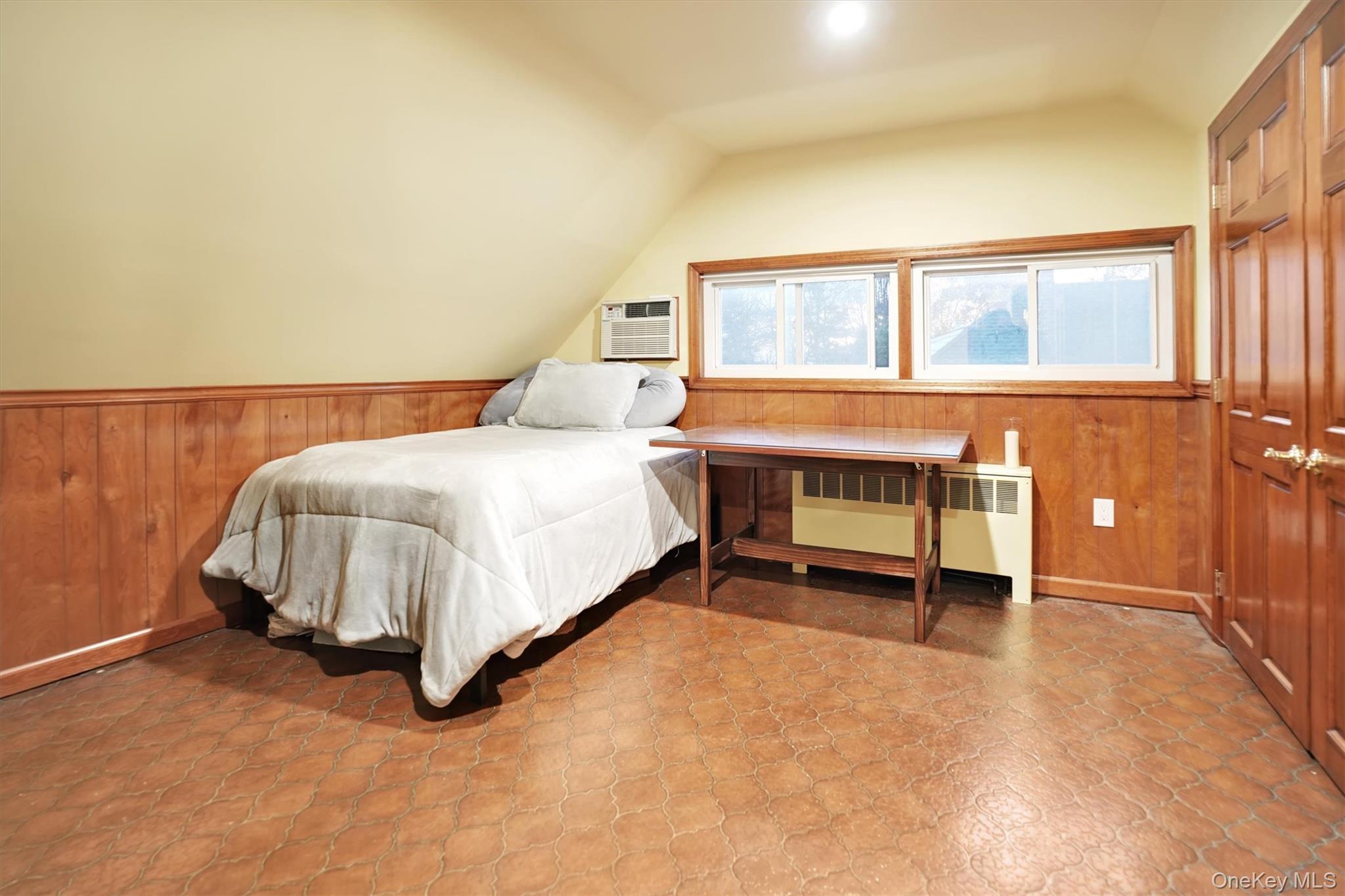 43 Ribbon Lane Wantagh, NY 11793 - Photo 23 of 36 Bedroom featuring wood walls, wainscoting, radiator, vaulted ceiling, and a wall unit AC