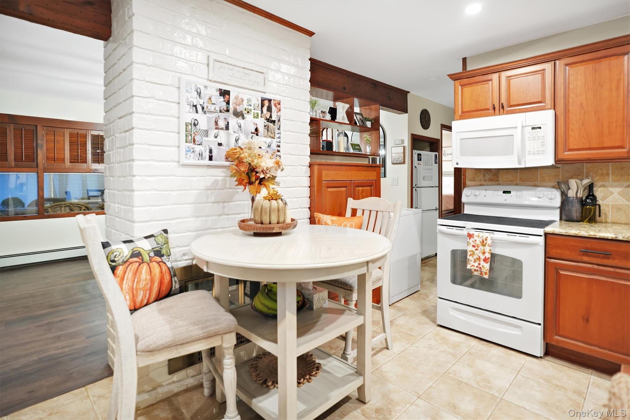 43 Ribbon Lane Wantagh, NY 11793 - Photo 8 of 36 Kitchen featuring white appliances, light stone counters, brown cabinetry, and light tile patterned floors