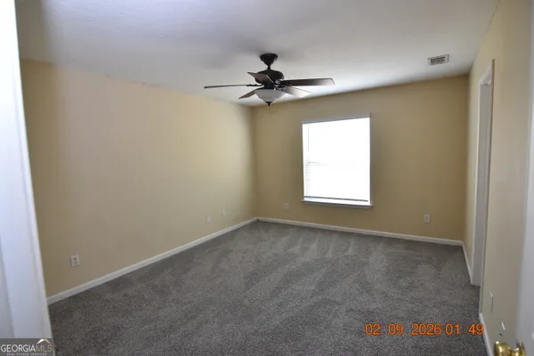 an empty room with windows and fan