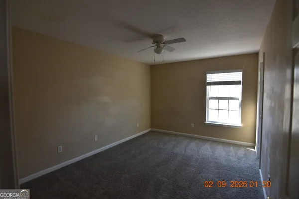 an empty room with windows and fan