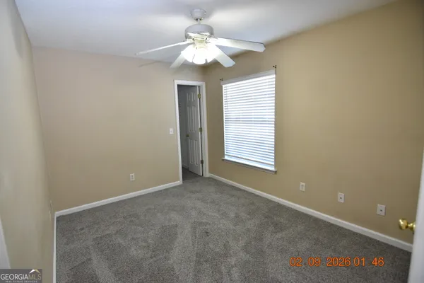 an empty room with windows and chandelier fan