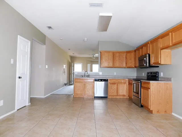 a large kitchen with stainless steel appliances granite countertop a stove a sink a refrigerator and white cabinets