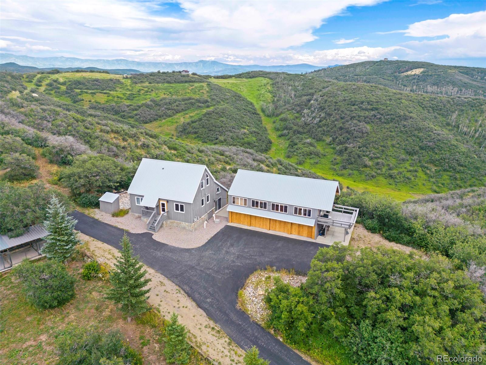 an aerial view of a house with garden space and mountain view in back