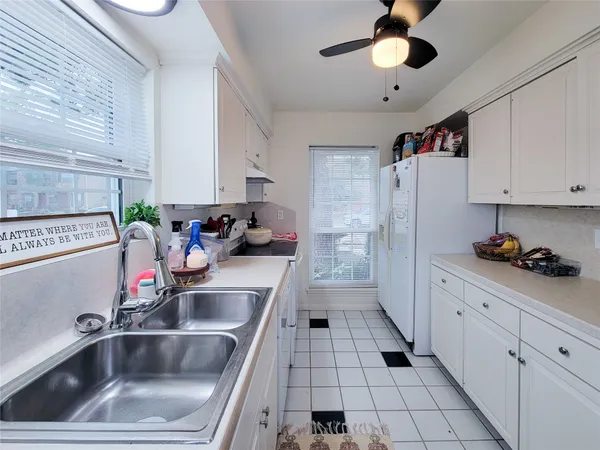 a kitchen with a sink dishwasher and white cabinets with wooden floor