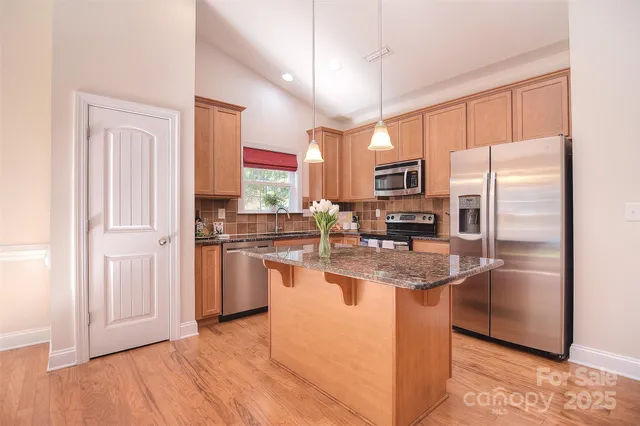 a kitchen with stainless steel appliances granite countertop a refrigerator a stove a sink and a microwave