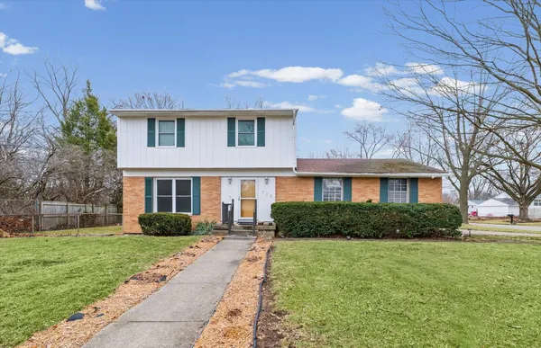 a front view of a house with a yard and trees