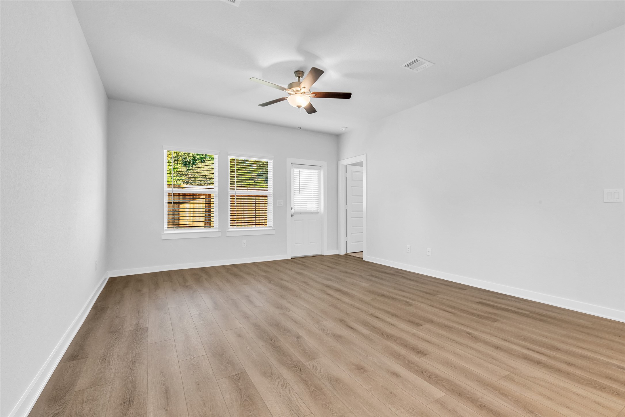 8550 Blueberry Ash Street Magnolia, TX 77354 - Photo 17 of 40 an empty room with wooden floor chandelier fan and windows