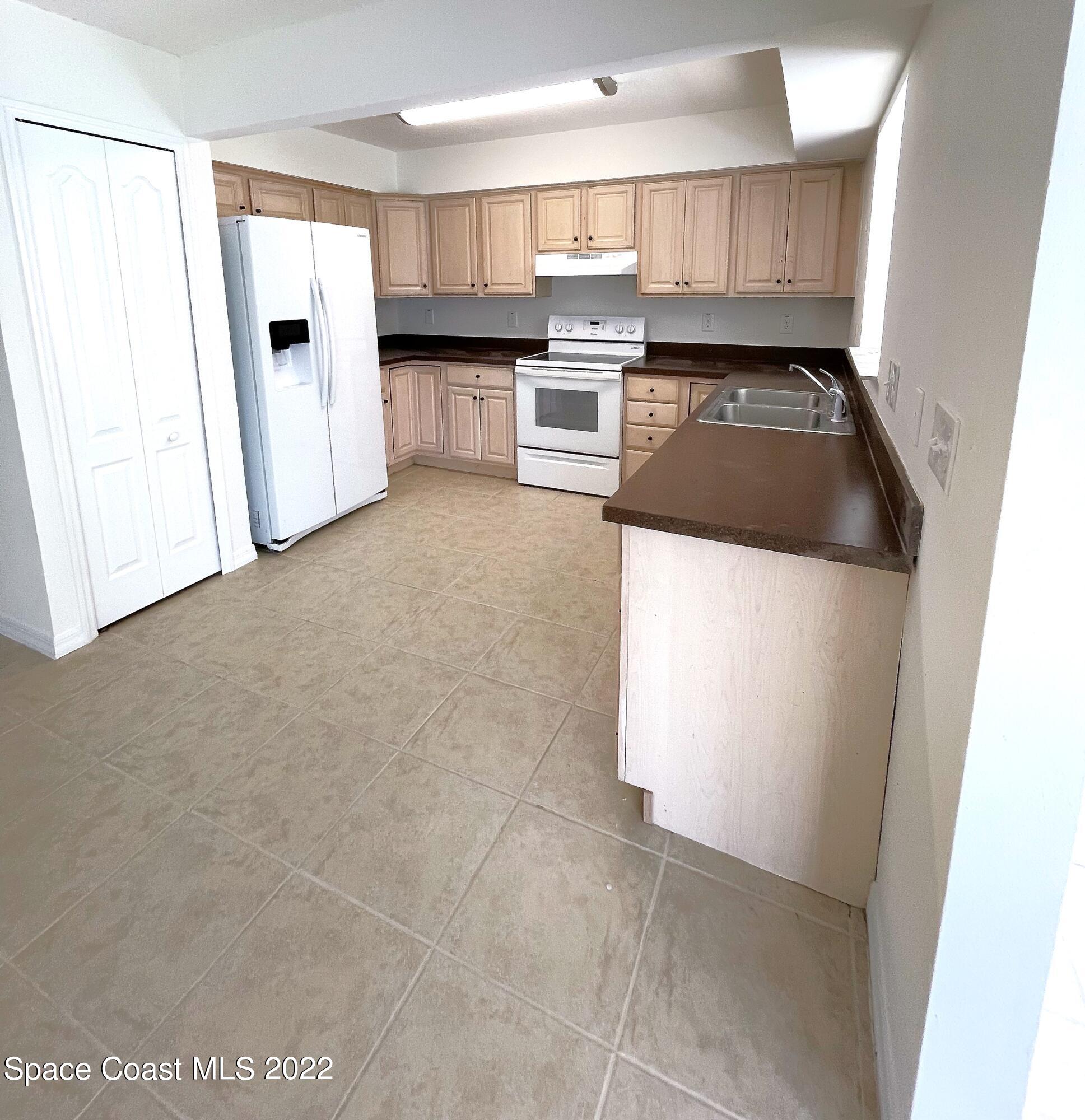 1440 Creel Road Northeast Palm Bay, FL 32905 - Photo 13 of 27 a kitchen with granite countertop a refrigerator a sink a stove a microwave and cabinets