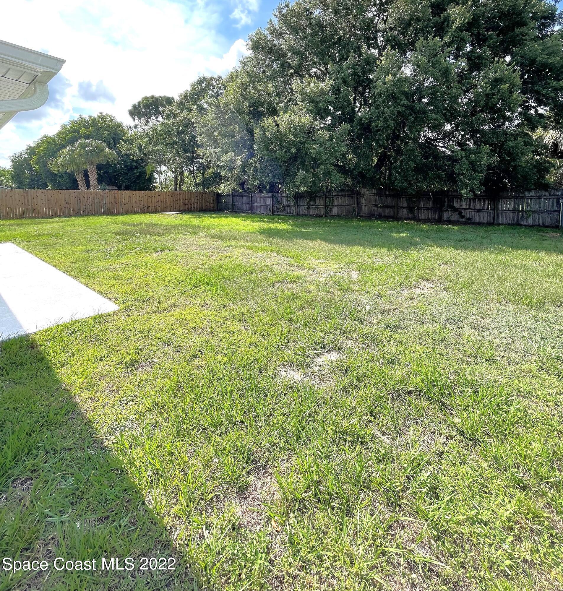 1440 Creel Road Northeast Palm Bay, FL 32905 - Photo 7 of 27 a view of a large yard with plants and large trees