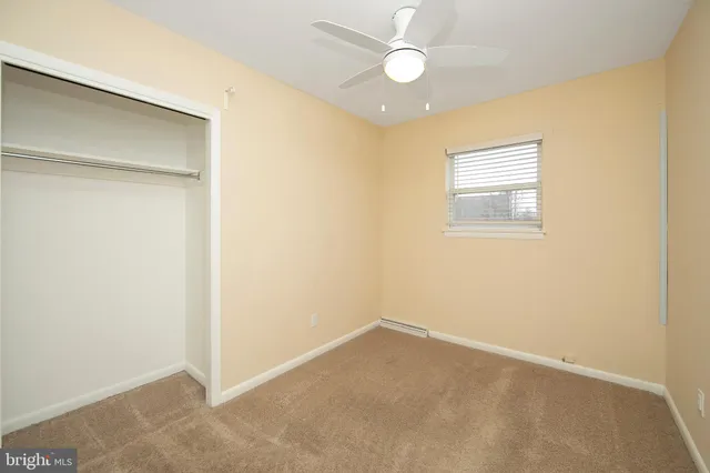 an empty room with a chandelier fan and windows