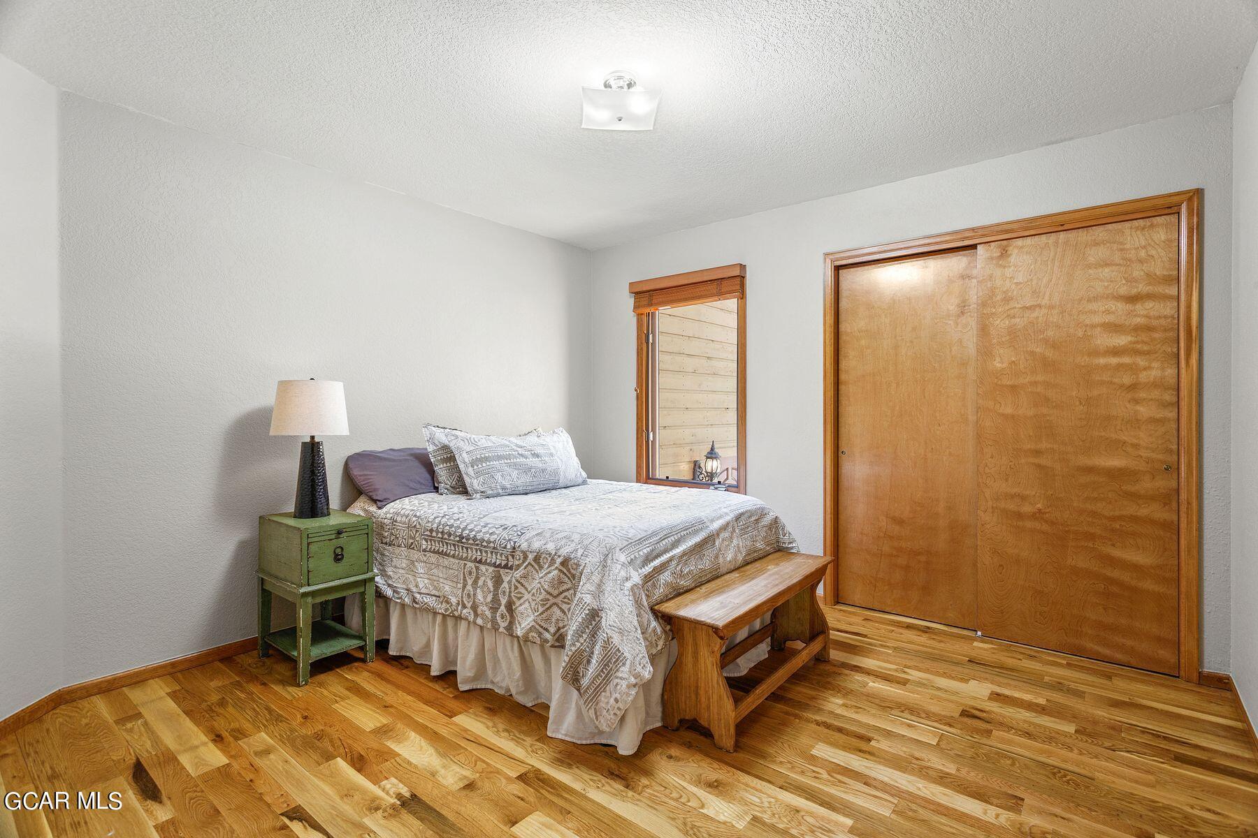 30539 Rand Road Conifer, CO 80433 - Photo 17 of 36 a bedroom with a bed and wooden floor