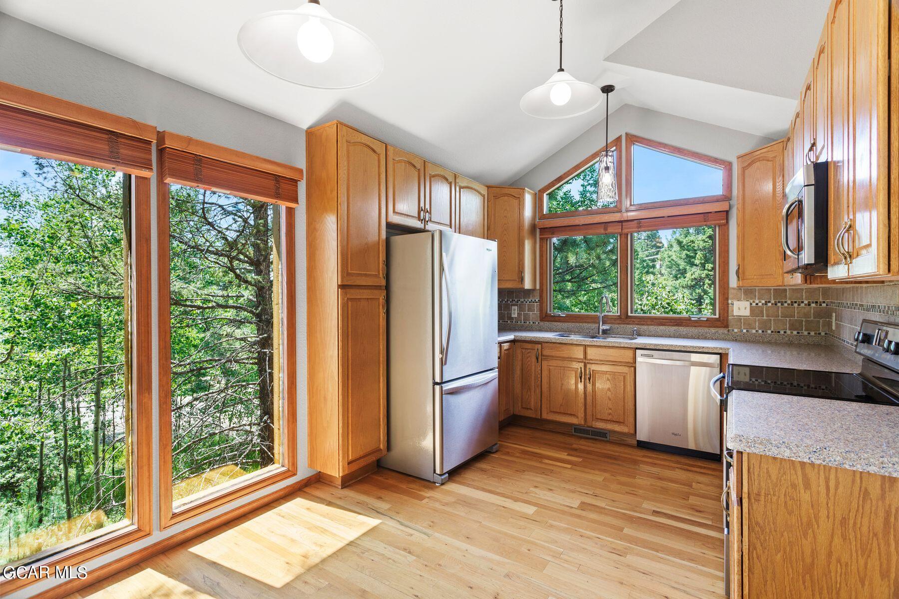 30539 Rand Road Conifer, CO 80433 - Photo 3 of 36 a kitchen with stainless steel appliances granite countertop a refrigerator a stove a sink and wooden floors