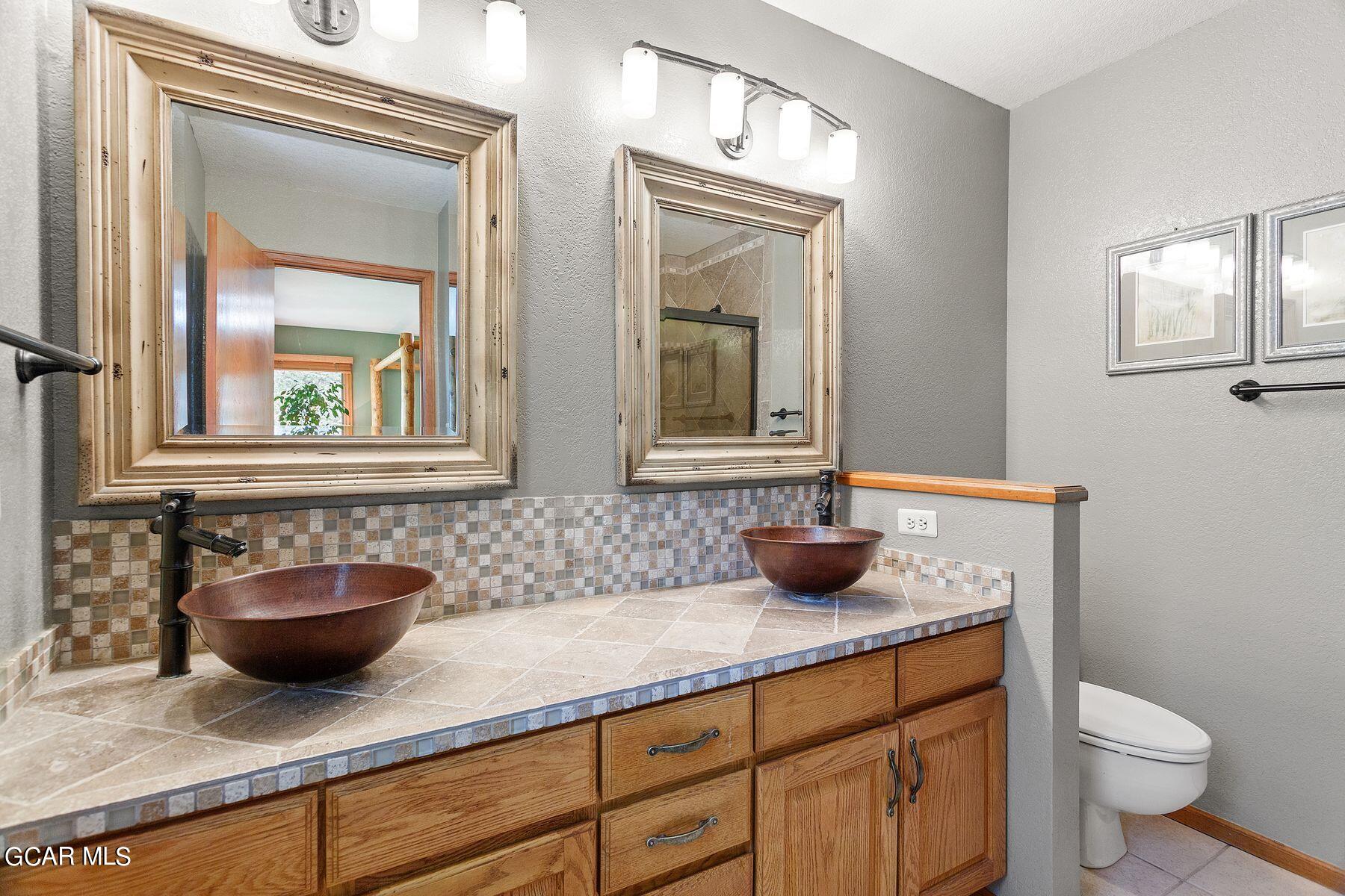 30539 Rand Road Conifer, CO 80433 - Photo 5 of 36 a bathroom with a granite countertop sink a toilet and mirror
