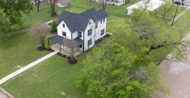 a view of a house with a big yard and large trees