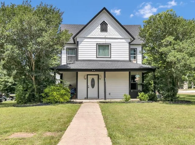 a front view of a house with a yard and trees