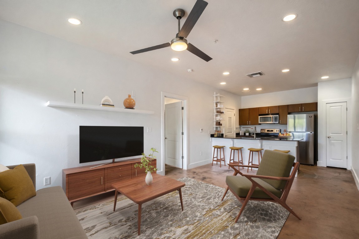 a living room with furniture a flat screen tv and kitchen view