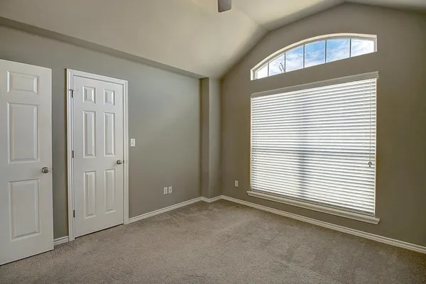 an empty room with chandelier fan and windows