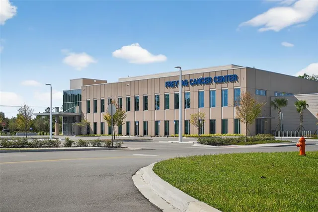 a front view of a building with a garden and trees