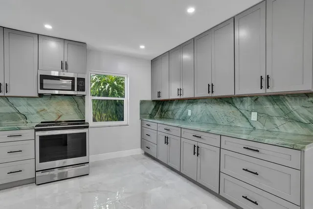 a kitchen with stainless steel appliances granite countertop a stove a sink and a microwave