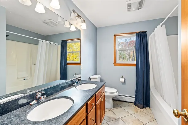 a bathroom with a granite countertop double vanity sink a mirror and a toilet