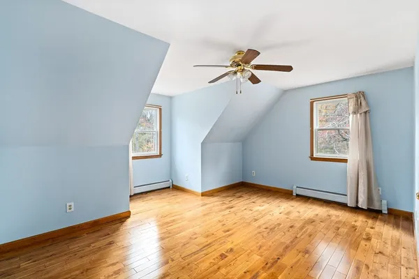 a view of a big room with wooden floor ceiling fan and windows